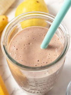 a smoothie in a mason jar with a blue straw and two lemons on the side