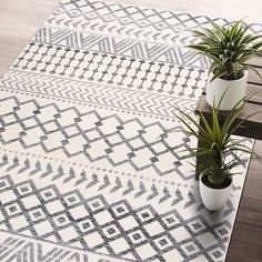 two potted plants sit on top of a wooden table next to a white rug