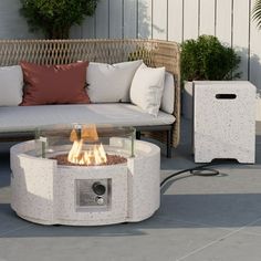 a fire pit sitting on top of a patio next to a white couch and table