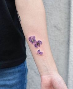 a woman's arm with purple flowers on the left side of her wrist and an arrow in the middle