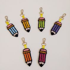 four crocheted pencils hanging from hooks on a white surface with yellow clips