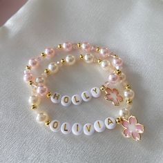 Flower Girl Bracelets personalized with her monogram initial make a pretty gift for any little girl in your bridal party.  The bracelet is made with faux pearls and alternating 18K gold-plated beads. Beaded Bracelets Name, Flower Girl Bracelet, Personalized Pink Bracelets As Personalized Gift, Personalized Pink Bracelets For Gifts, Customized Pink Charm Bracelet For Personalized Gift, Personalized Pink Beaded Bracelets With Name, Personalized Pink Charm Bracelet For Birthday, Flower Charm Bracelet For Birthday, Personalized Adjustable Pearl Bracelet For Birthday