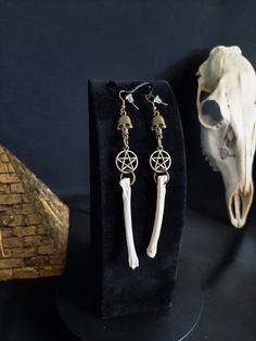 Here is a Nice Pair of Coyote Bone earrings! They Were Made with Bronze Pentagram and Skull Charms. These Earrings are 5 Inches Long. All Items Ship Within 1-3 Days via USPS First Class Service, With Some Upgrades Available Also. Shipping on These Will be 5.00 Additional Items are Free! International Shipping Will Be 20.00, And All Additional Items Are FREE! International Shipping May Take 2 - 6 Weeks To Deliver. I Always Love to Accommodate Custom Orders! If you Have Something in Mind , Please Message me. Have a Drawing or a Photo of Your Inspiration and Send it to Me! And Also Please Send Me Your Preferred Budget For Your Piece, To Make Sure You are Not Overcharged. I DO NOT Carry Human Bones or Any Sort Of Illegal Items. And As Etsy Sellers, We Are Not Allowed to Sell Domesticated Dog o Dice Jewelry, Earrings Goth, Earrings Gothic, Witch Earrings, Goth Earrings, Human Bones, Bone Earrings, Bone Jewelry, Gothic Earrings