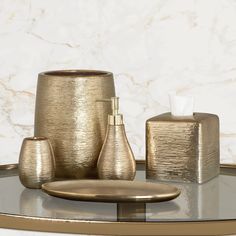 gold bathroom accessories sitting on top of a glass table