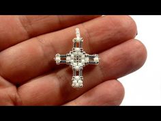 a hand holding a small white beaded cross