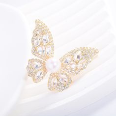 Embrace elegance with our Butterfly Brooch, featuring a radiant 8-9mm freshwater pearl nestled among sparkling cubic zirconia. Available in gold and silver finishes, this exquisite piece adds a touch of sophistication to any outfit. A perfect gift to symbolize transformation and beauty Material: Gold plated on brass, cubic zirconia, and freshwater pearls Pearl Size: 8-9mm Note: Our jewelry is handmade. Naturally formed shapes of freshwater baroque pearls may vary. The actual product may be sligh White Diamond Wedding Brooches, Elegant Diamond White Brooches For Wedding, Elegant Diamond White Wedding Brooches, Elegant Gold Diamond Brooch, Elegant Gold Brooches With Diamond Accents, Elegant Diamond White Brooch For Gift, Elegant Diamond White Brooches As Gifts, Elegant Diamond White Brooches For Gift, Elegant Cubic Zirconia Brooch Jewelry