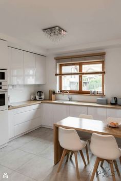 a kitchen with white cabinets and counter tops next to a dining table in front of a window