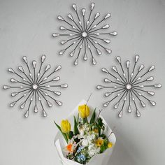 flowers are arranged in the shape of sunbursts on a white wall with water droplets