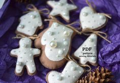 some decorated cookies are sitting on a purple table cloth with pine cones and twinklings