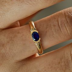 a woman's hand with a gold and blue ring on top of her finger