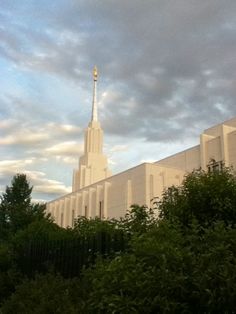 a tall white building with a steeple on it's side and trees in the foreground