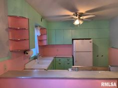 an empty kitchen with pink and green cabinets, white appliances and a light fixture on the ceiling