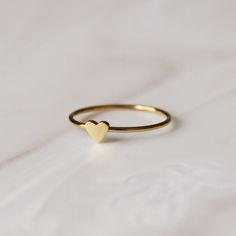 Photo of a thin gold ring with a small gold heart on it sitting on a marble surface. Rose Gold Heart Ring, Jewelry Wishlist, Gold Heart Ring, Silver Heart Ring, Jewellery Inspiration, Rose Gold Heart, Tiny Heart, Charm Rings, Mini Heart