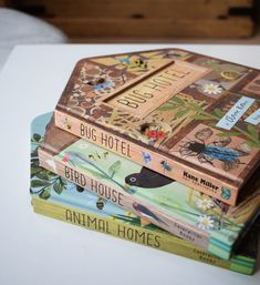 three books stacked on top of each other in front of a wooden box with animals