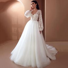 a woman in a white wedding dress standing next to a wall with her hand on her face