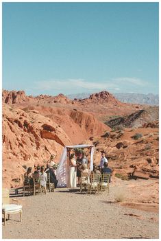 an outdoor ceremony in the desert with people sitting at chairs and one person standing on the ground