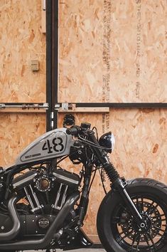 a black and silver motorcycle parked in front of a wooden wall