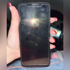 a woman's hand holding up a cell phone with the sun shining through it