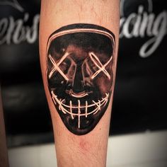 a man's leg with a tattoo on it that has an image of a mask