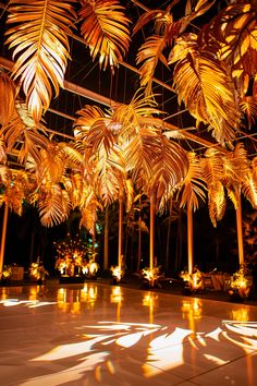 an indoor area with lights and palm leaves hanging from it's ceiling, lit by candles