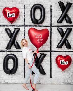 a woman standing in front of giant balloons with the word love spelled on them and holding a red leash