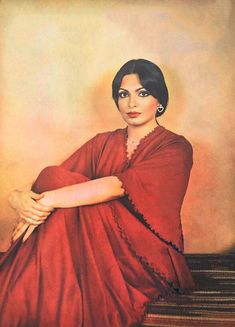 an old photo of a woman in a red dress sitting on the floor with her arms crossed