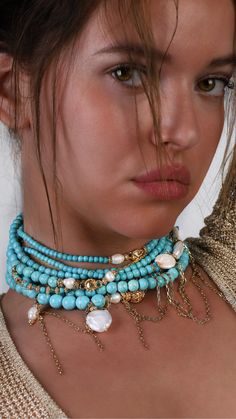 a close up of a woman wearing a necklace with pearls and beads on her neck