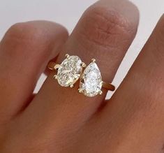 a woman's hand with two pear shaped diamond rings on top of her finger