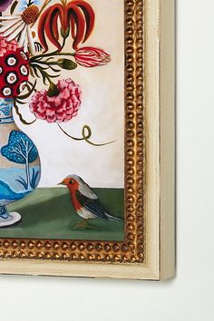 a painting hanging on the wall with a bird and flowers in a vase next to it