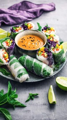 a plate with some food on it and garnished with limes next to a bowl of dipping sauce