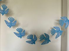 blue paper birds are hanging from the wall