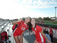 two girls in red shirts standing next to each other at a soccer game on the field