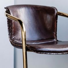 a brown leather chair with gold metal arms