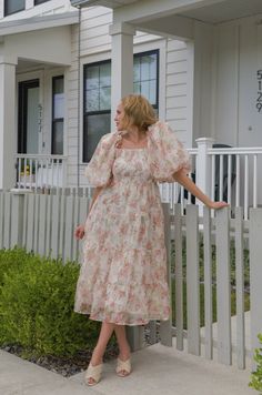 Expertly crafted with a peachy floral chiffon fabric, this midi dress features delicate puff sleeves, a smocked back zipper, and tiered design. Perfect for any occasion, this dress combines style and comfort for a flawless look. peachy floral print chiffon midi length puff sleeves square neckline smocked bodice back zipper closure true to size hand wash cold model is wearing a small and model is 5'5" Billowy Midi Dress For Spring Garden Party, Billowy Feminine Dress For Garden Party, Feminine Flowy Floral Dress With Puff Sleeves, Airy Spring Midi Dress For Daywear, Spring Ruched Chiffon Midi Dress, Spring Chiffon Midi Dress With Ruched Details, Midi Chiffon Dress With Ruffles For Garden Party, Tiered Puff Sleeve Dress For Garden Party, Midi-length Chiffon Dress With Ruffles For Garden Party