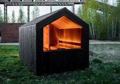 an outdoor sauna in the middle of a grassy area with trees and a sign above it