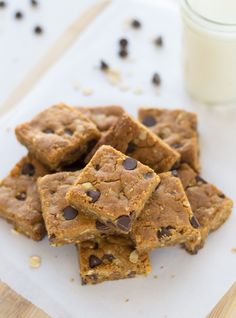 chocolate chip cookie bars on a cutting board next to a glass of milk