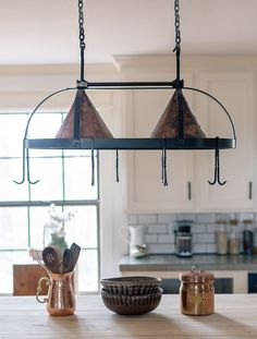 a kitchen island with two hanging lights and bowls on the counter top in front of it