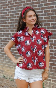 No clichés here - just touchdown-worthy fashion with our Seminoles Poplin Blouse! This playful and lightweight woven cotton blouse features a collar, button front, and classic, relaxed fit. With an all-over Seminole logo print, this blouse will have you cheering for more! Details: *OFFICALLY LICENSED* Soft, Poplin, Woven Fabric Material 100% Cotton Functional buttons on chest, High collar, Cap Sleeve Features Seminole Head all over Shirt Color: Garnet True to Size: Classic Ladies Fit Natalee is Casual All Over Print Tops For Work, Casual Tops With All Over Print For Work, Cotton Button-up Blouse With Graphic Print, Printed Cotton Blouse For Work, Tallahassee Florida, Poplin Blouse, Fashion Bottoms, Florida State University, Florida State Seminoles