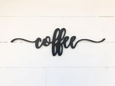 a metal sign that says coffee hanging on the side of a white wall with wood planks