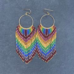 These bright rainbow beaded fringe hoop earrings are handwoven around 14k gold filled wire hoops and strung one bead at a time with Miyuki delica glass seed beads (the shiny gold beads are 24k gold plated). This is my "Rainbow Warrior" design in bright rainbow. I also have a muted rainbow warrior color palette that I make with matte 24k gold plated beads. These earrings are a tactile experience! They feel wonderful with their natural swing and delightful shimmer. Super lightweight despite their Rainbow Hand-strung Round Jewelry, Bohemian Heishi Beads Dangle Jewelry, Bohemian Dangle Jewelry With Heishi Beads, Multicolor Hand-strung Dangle Jewelry, Bohemian Hoop Beaded Earrings With Heishi Beads, Bohemian Heishi Beaded Hoop Earrings, Bohemian Hoop Earrings With Heishi Beads, Rainbow Heishi Beads For Jewelry Making, Hand-strung Rainbow Jewelry For Festivals