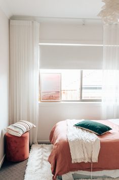 a bedroom with white curtains and pink bedding