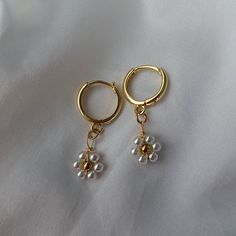 🖊️ Product details 🖊️ Handmade 18K Gold Plated Brass huggie earrings. Suitable for sensitive ears.  Flower charm: 1cm in diameter, stainless steel material  Huggie: 1.4cm in diameter Earring pin: 1mm 🫶 Product care 🫶 - To avoid your jewellery tarnishing from moisture and liquids, please refrain from wearing then in places such as pools and during intense exercise.  - Keep your jewellery protected from the sun and safe from scratches and chips. It's best if you store your jewellery in air tight space.  - Our jewellery are handmade with love, so please handle them carefully 😊 💌 Handling 💌 Please allow for 1-2 business days for your pieces to be made and packaged with care.  Your order will be shipped in a padded envelope to ensure that your jewellery arrives safely.  💛 Thank you for Earring Pins, Sleeper Earrings, Stacked Jewelry, Huggie Earrings, Flower Charm, White Beads, Sensitive Ears, Huggies Earrings, Steel Material