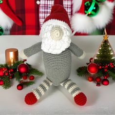 a crocheted stuffed animal wearing a santa claus hat and standing next to christmas decorations