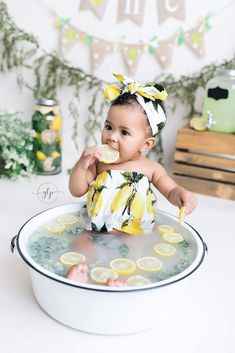 a baby sitting in a tub with lemons on it