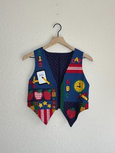 Vintage 90's handmade Back to School vest. Size- estimated kids 6/8. please check measurements. Length- 14 in in back, 19 in in front Width- 16 in ptp  Excellent vintage condition. Buttons are for decoration. Retro Multicolor Cotton Vest, Retro Cotton Patchwork Vest, 90s School, School Theme, School Themes, Fort Collins, Kids Tops, Halloween Shopping, Fort