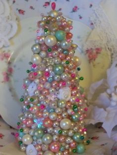 a white plate topped with a christmas tree made out of pearls and other decorations on top of it