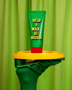 a green container with a yellow tray on top of it and a tube of face mask next to it