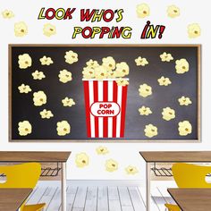 a popcorn bucket sitting in front of a chalkboard with the words, look who's popping in