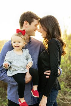 a man and woman holding a baby girl in their arms while standing next to each other