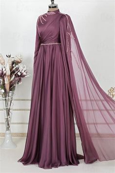 Step into elegance with this exquisite Full-Length Evening Gown. Crafted in a rich shade of deep plum, this gown features a luxurious chiffon fabric that drapes beautifully, creating a silhouette that flatters every figure. The delicate beading along the high neckline and waist adds a touch of sparkle, while the sweeping floor-length skirt ensures you make a grand entrance at any event.The intricate detailing on this gown sets it apart. A unique cross-body draping design adds depth and sophistication, while the sheer cape sleeve, adorned with beaded accents, cascades gracefully, offering a touch of drama and elegance. The concealed back zipper ensures a seamless fit, making this gown as comfortable as it is stunning.Ideal for evening soirées, weddings, or formal occasions, this Full-Length Purple Gown With Sweep Train For Banquet, Purple Evening Dress With Sweep Train For Banquet, Pre-draped Silk Chiffon Floor-length Gown, Pre-draped Georgette Evening Dress, Wedding Evening Dress With Draped Sweep Train, Draped Evening Dress With Sweep Train For Wedding, Purple Floor-length Dress For Banquet, Pre-draped Long Sleeve Wedding Gown, Chiffon Floor-length Prom Gown